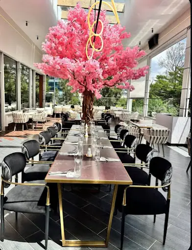 Long communal table under a blossom installation, terrace seating